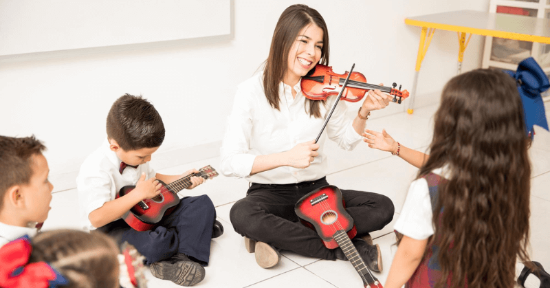 Playing violin Music teacher showing kids how to play violin