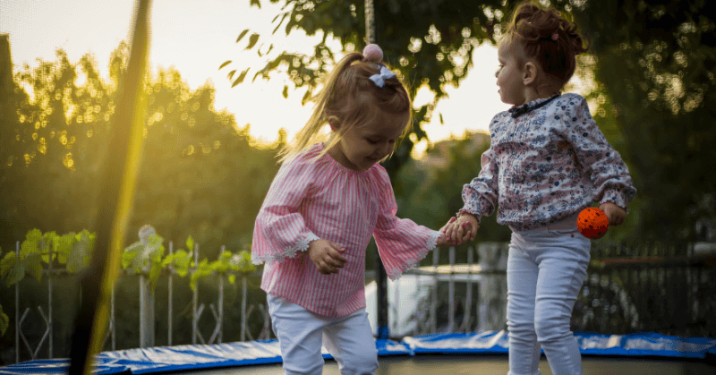 Two little girls standing on a trampoline Two little girls standing on a trampoline