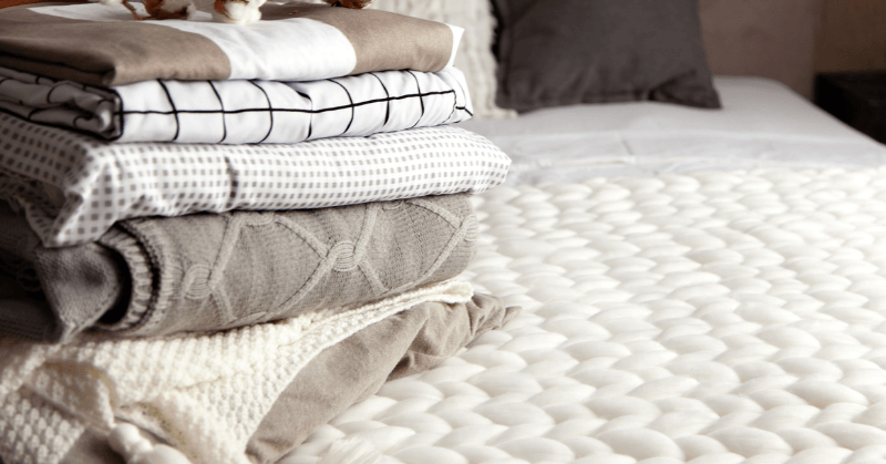 Folded linens on a white quilt Folded linens on a white quilt