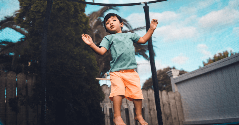 Little boy jumping inside a netted trampoline Little boy jumping inside a netted trampoline