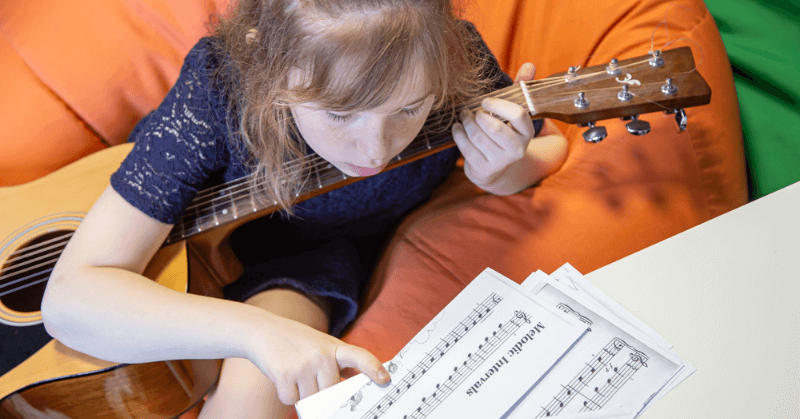 Young girl looking at chords Young girl reading sheet music while playing guitar