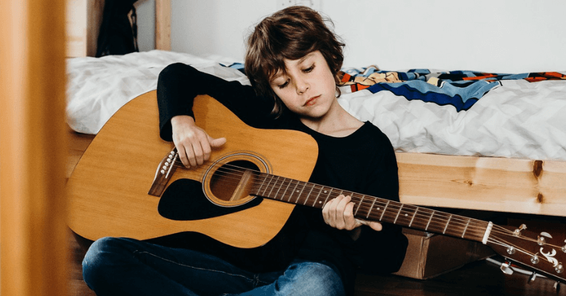 Young guitar player practising Young boy practising on a full-sized guitar